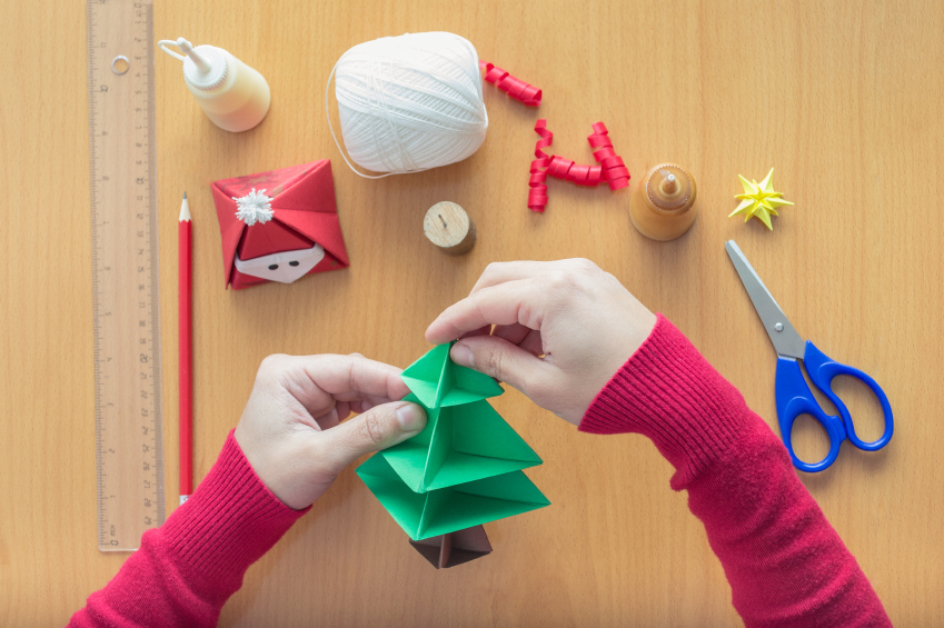 Weihnachtlicher Basteltisch, eine Mutter faltet einen Baum